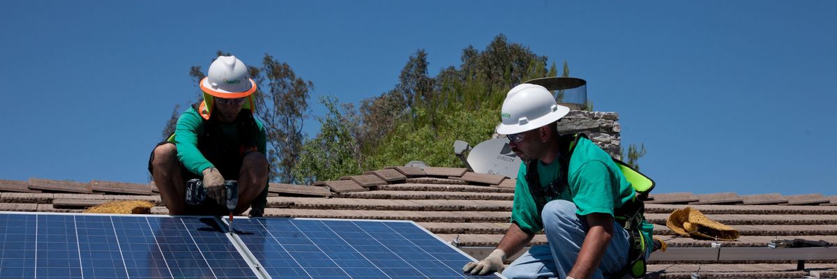 Two workers install solar panels on a home in Oak View, California on August 23, 2011. 