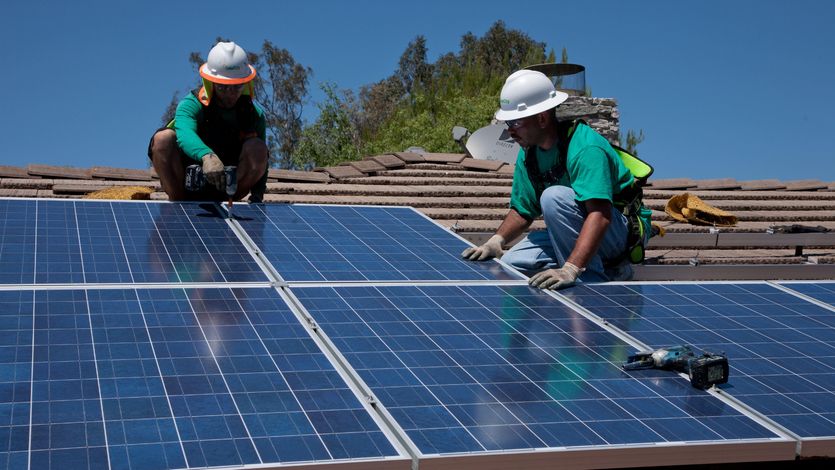 Two workers install solar panels on a home in Oak View, California on August 23, 2011.