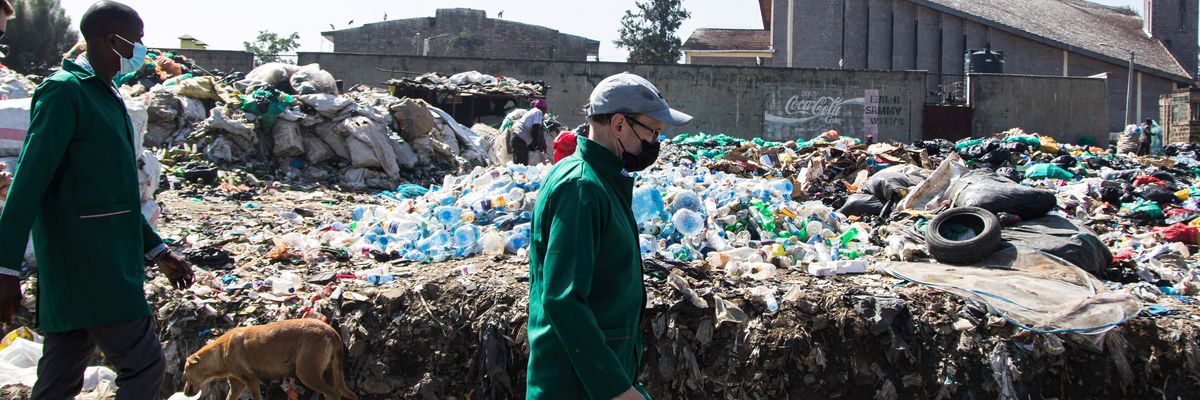 U.N. Environment Assembly President Espen Barth Eide walks past a heap of plastic bottle waste during a trip