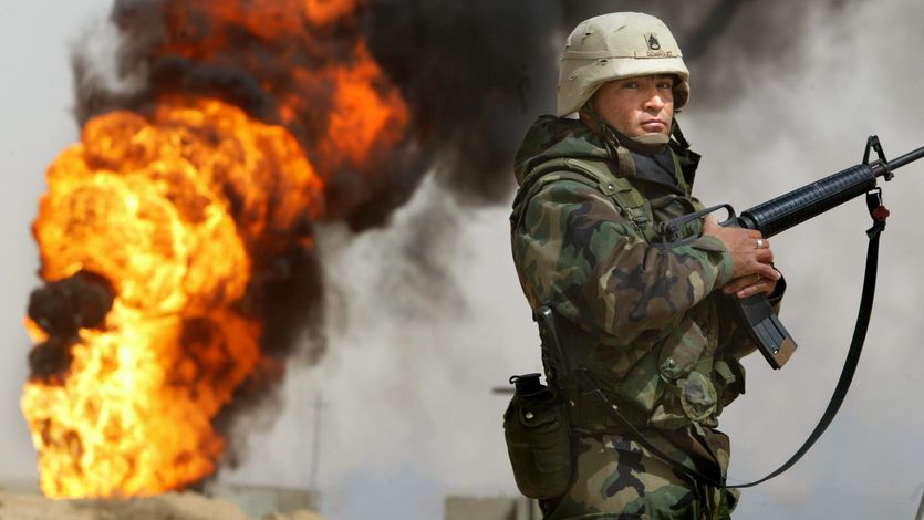 U.S. Army Staff Sergeant Robert Dominguez stands guard next to a burning oil well on March 27, 2003 in Rumayla, Iraq.