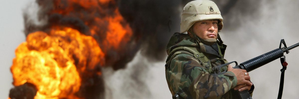 U.S. Army Staff Sergeant Robert Dominguez stands guard next to a burning oil well on March 27, 2003 in Rumayla, Iraq.