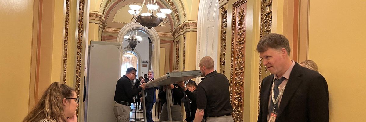 U.S. Capitol officials are seen removing metal detectors from in front of the House chamber