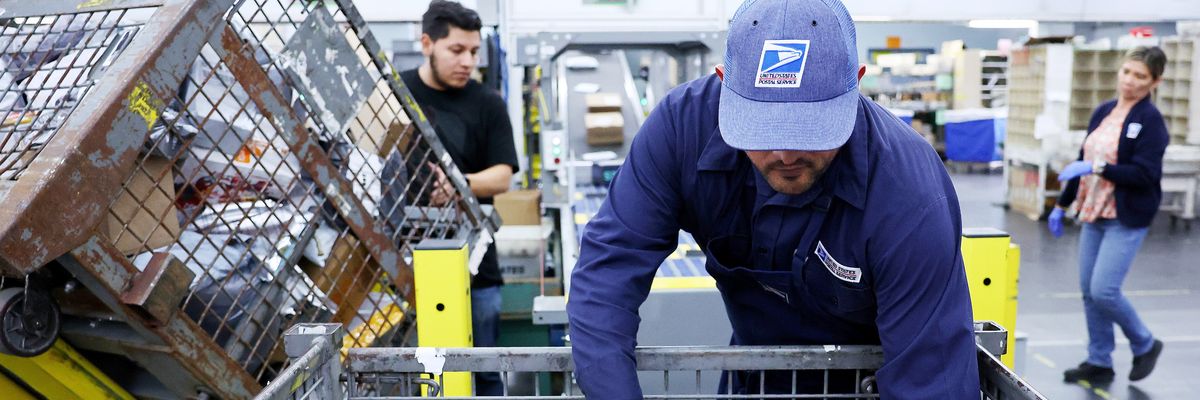 U.S. Postal Service employees place packages into a sorting machine