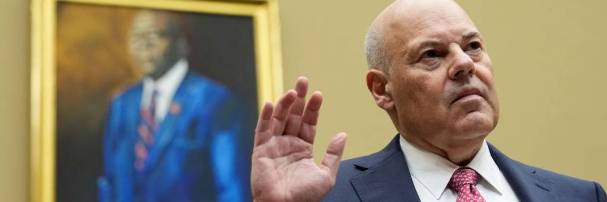 U.S. Postmaster General Louis DeJoy stands with his right hand raised.