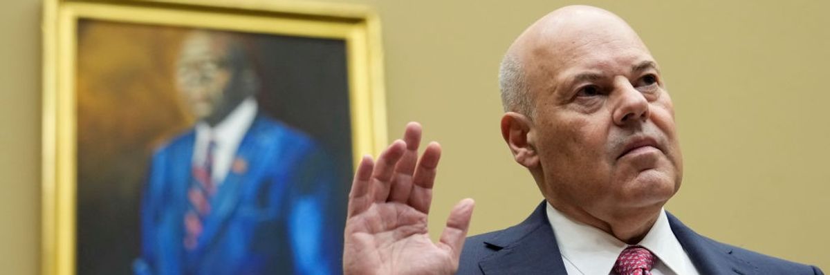 U.S. Postmaster General Louis DeJoy stands with his right hand raised.