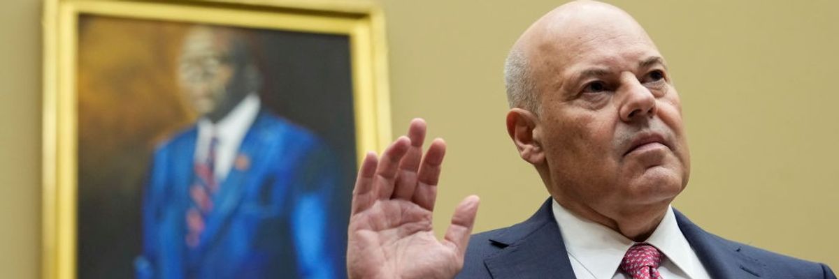 U.S. Postmaster General Louis DeJoy stands with his right hand raised.