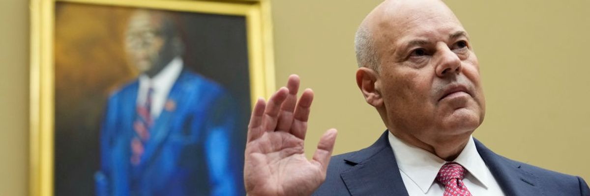 U.S. Postmaster General Louis DeJoy stands with his right hand raised.