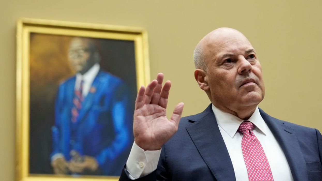 U.S. Postmaster General Louis DeJoy stands with his right hand raised.