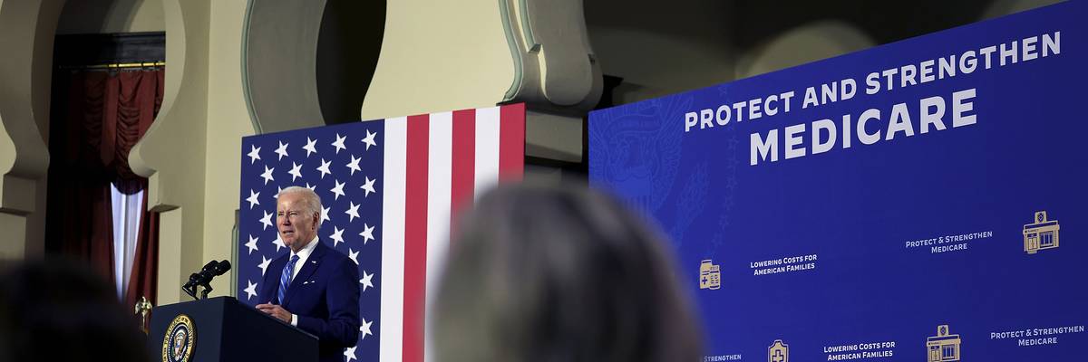 U.S. President Joe Biden speaks next to a sign saying, "Protect and strengthen Medicare."