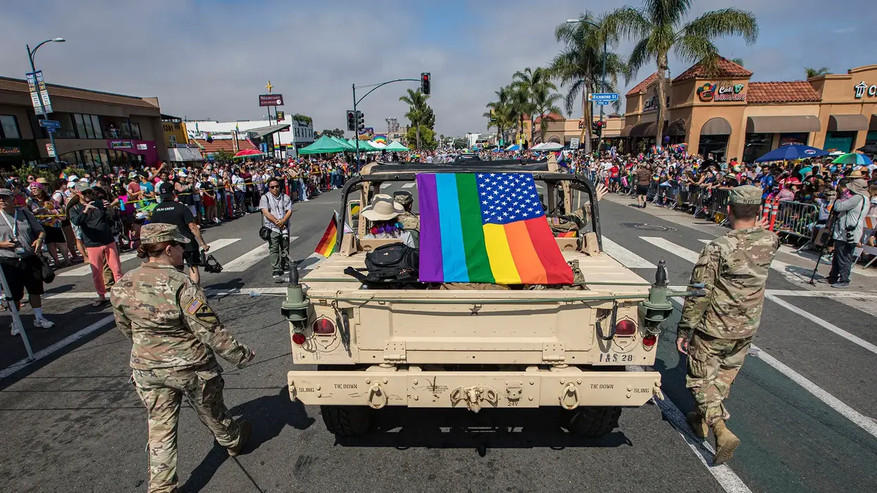 U.S. soldiers march in parade with rainbow American flag.
