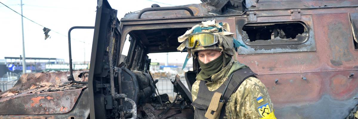 Ukraine soldier examines destroyed Russian military vehicle