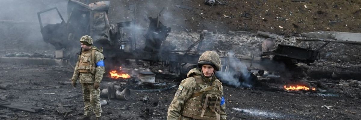 Ukrainian soldiers and burned out vehicle