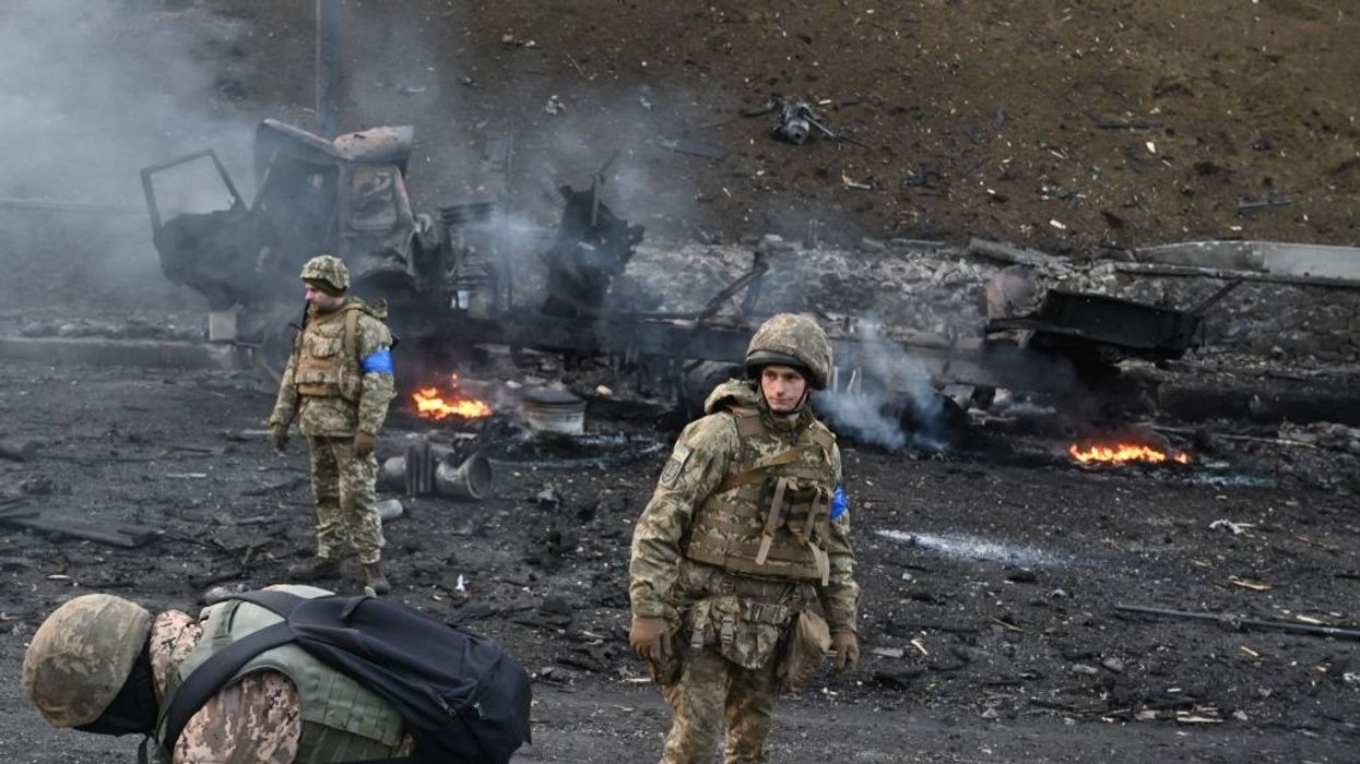 Ukrainian soldiers and burned out vehicle