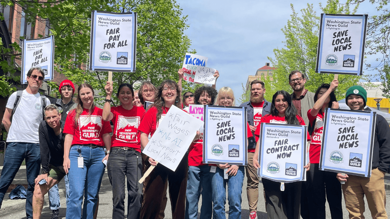 Unionized journalists in Washington state hold signs that say "save local news."