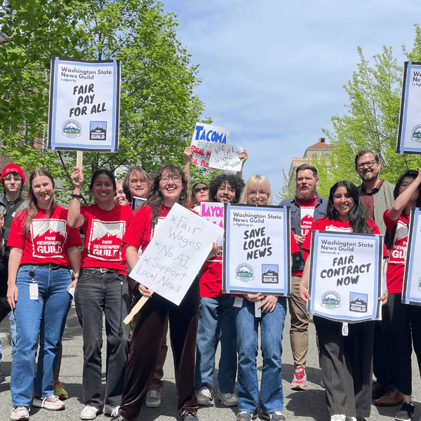 Unionized journalists in Washington state hold signs that say "save local news."