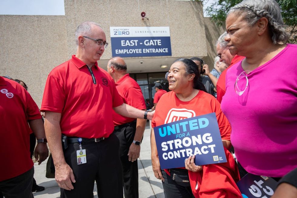 United Auto Workers president Shawn Fain greets a woman holding a 'United for a strong contract" sign.