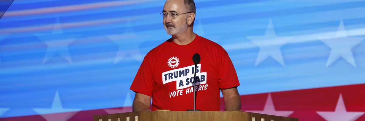 United Auto Workers president Shawn Fain wears a t-shirt reading, "Trump is a scab, vote Harris."