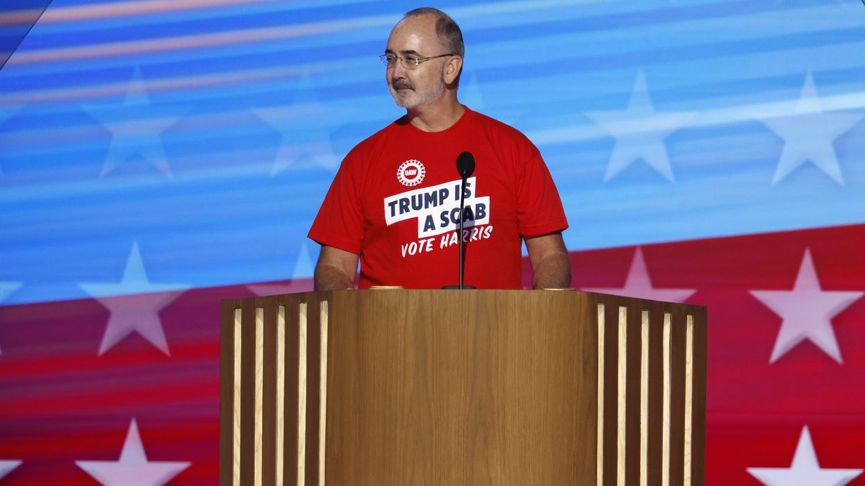 United Auto Workers president Shawn Fain wears a t-shirt reading, "Trump is a scab, vote Harris."