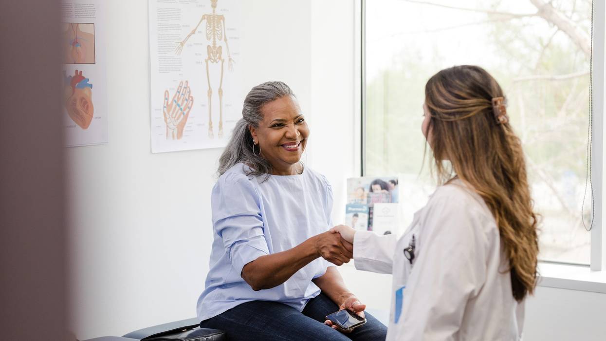 Unrecognizable doctor shakes hands with senior female patient