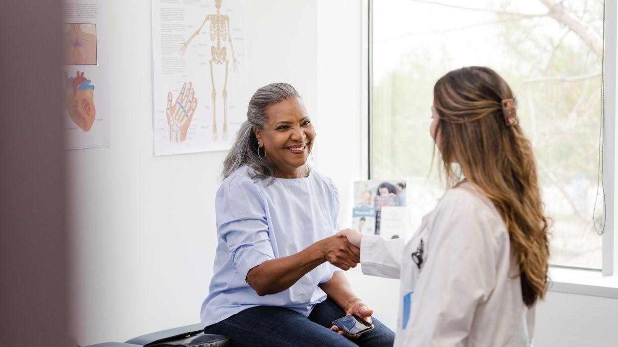 Unrecognizable doctor shakes hands with senior female patient
