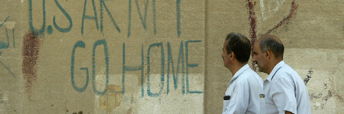 "US Army Go Home" Iraqi men walk past anti-US graffiti in Baghdad on October, 2003.