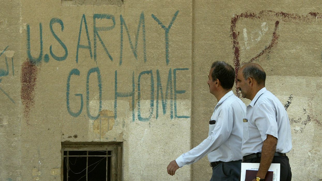 "US Army Go Home" Iraqi men walk past anti-US graffiti in Baghdad on October, 2003.