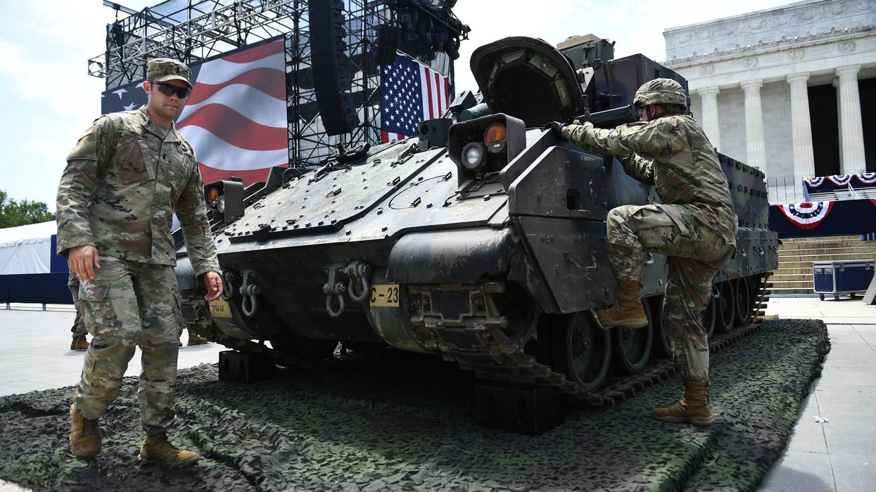 US military members next to a tank.