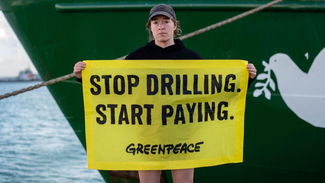 Usnea Granger, Greenpeace activist, holding a sign that reads: "Stop Drilling. Start Paying."