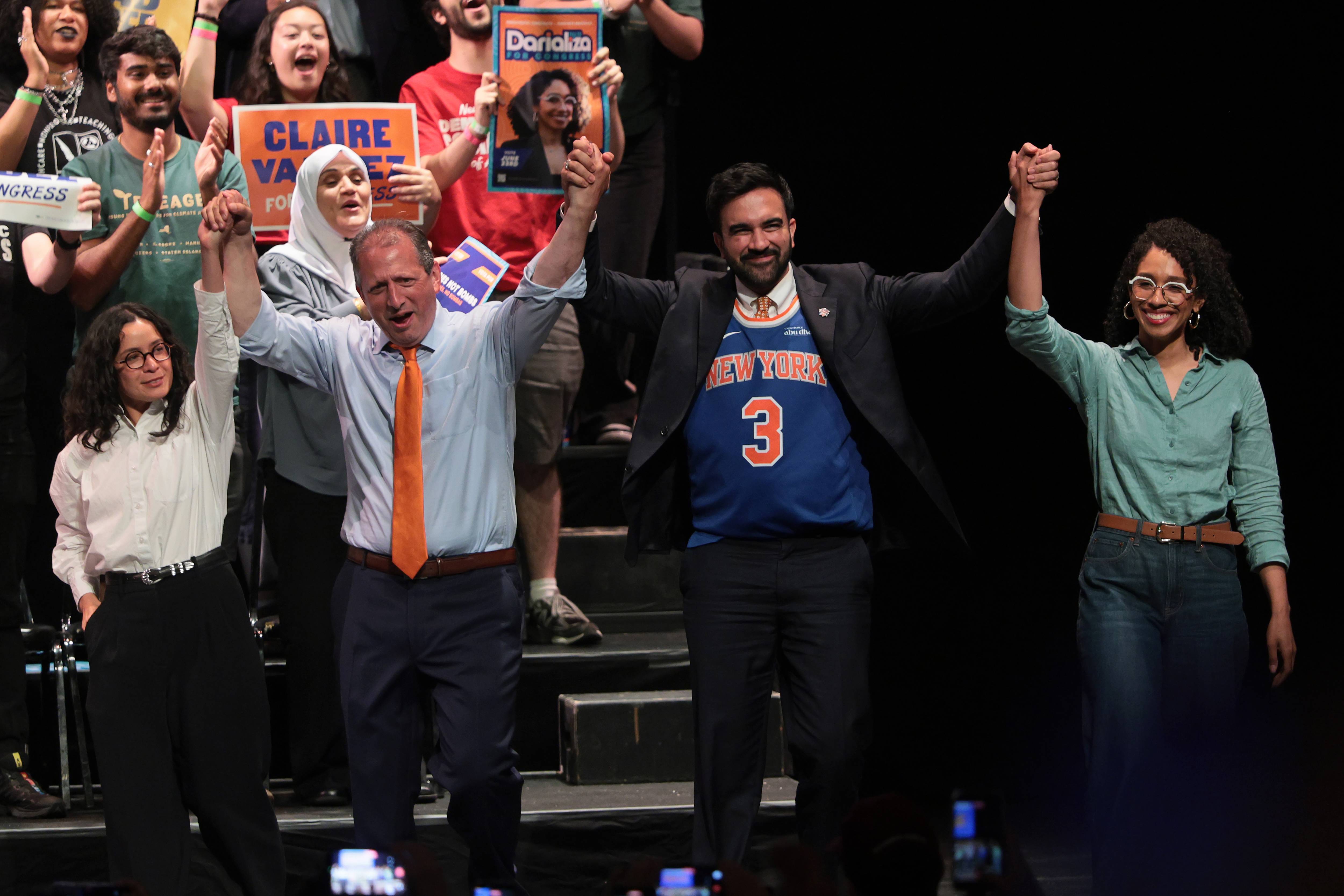 Valdez, Lander, Mamdani, and Chevalier hold raised hands at a rally.