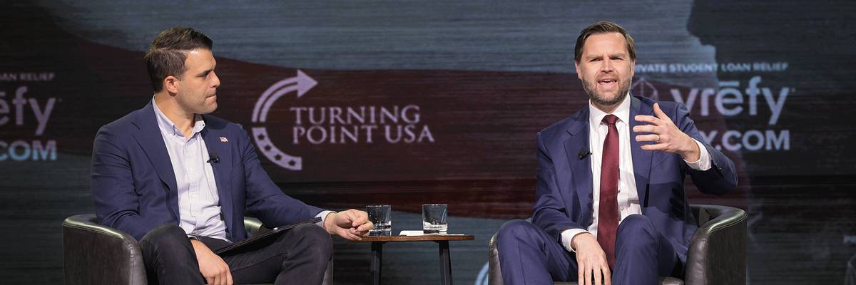 Vice President JD Vance sits in a chair and gestures toward the audience at a TPUSA event in Georgia
