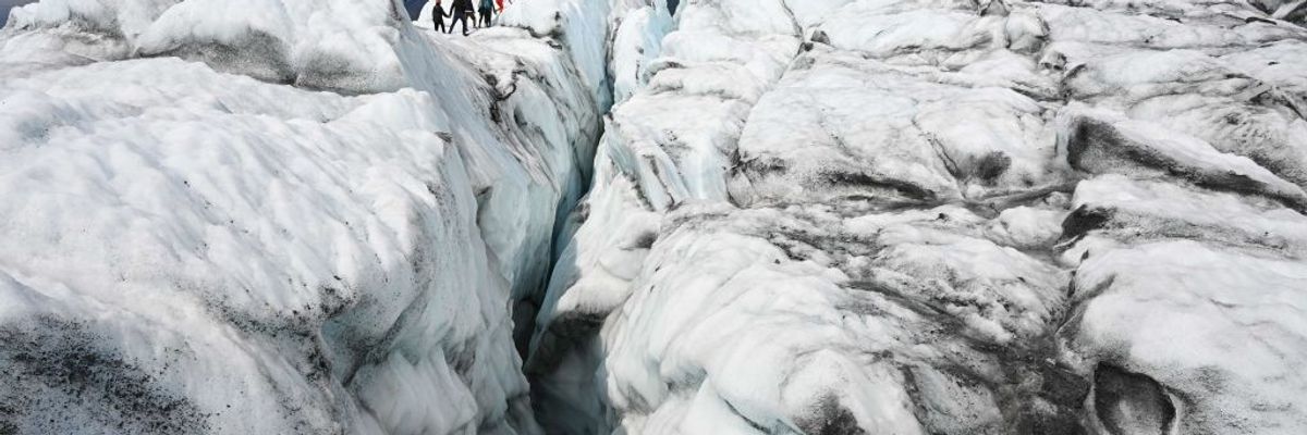 Visitors hike on the ice along a crevasse