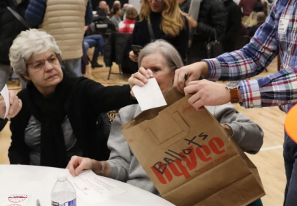 Voters at GOP Iowa caucus drop their ballots, torn from a notebook, in a grocery bag
