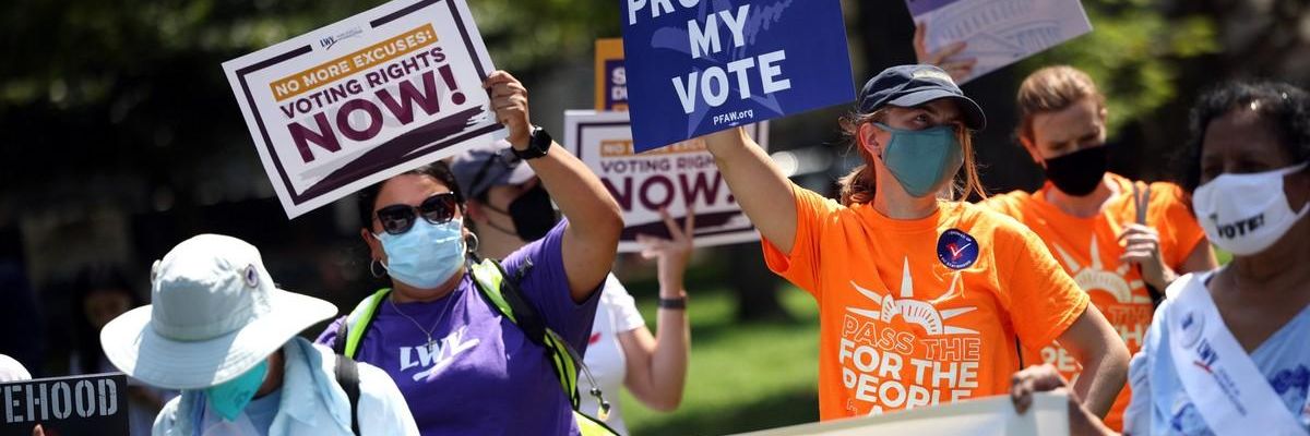 Voting rights activists hold signs at rally