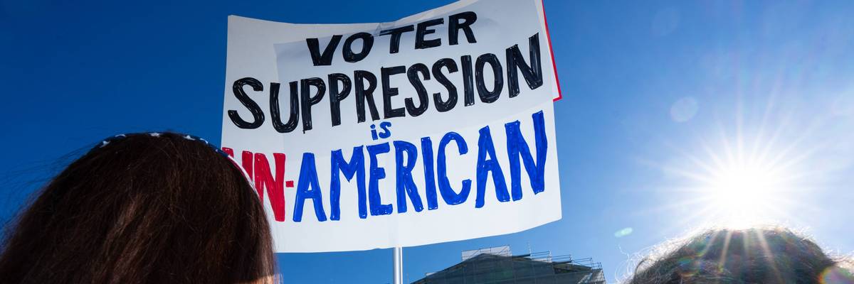 Voting rights protesters hold a sign reading "Voter Suppression Is Un-American" outside the Supreme Court