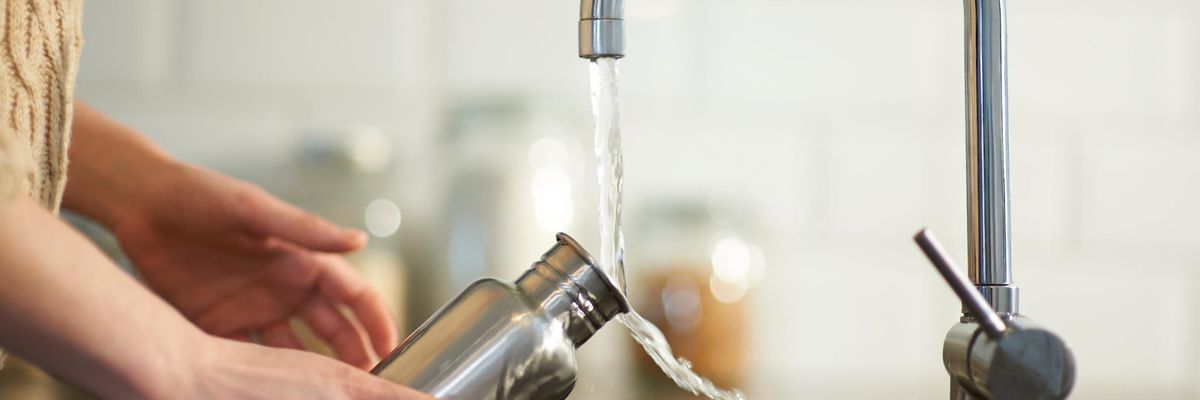 water flows from a sink faucet to a bottle