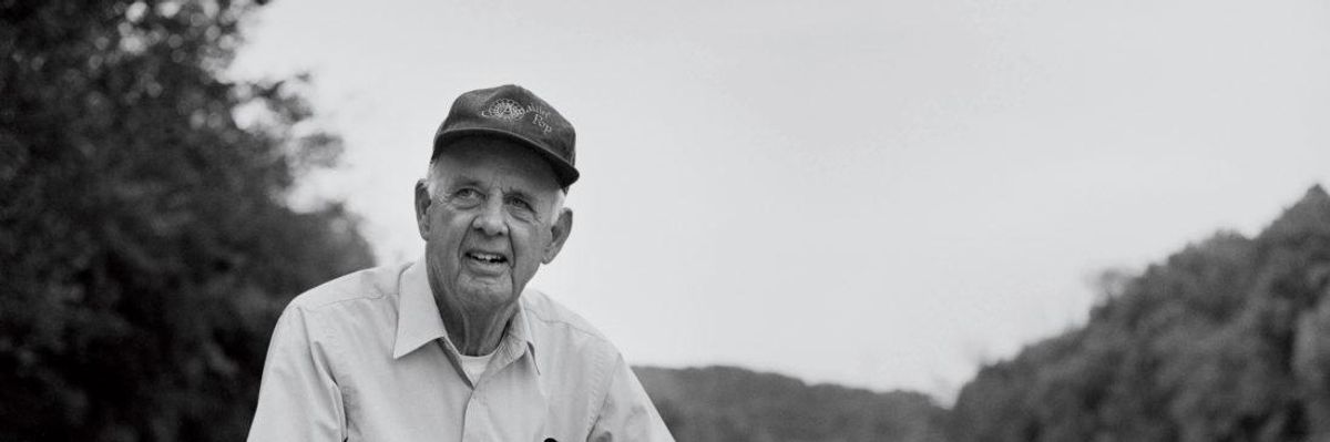Wendell Berry pictured with a dog by the Kentucky River