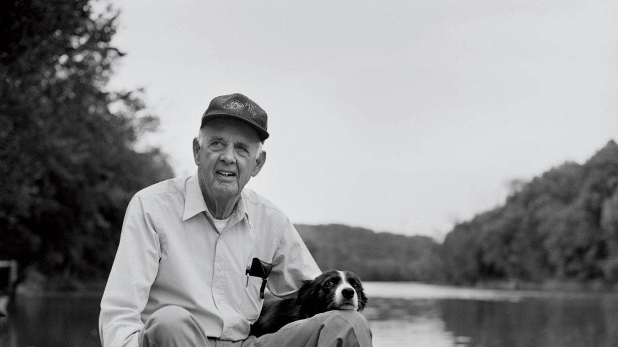 Wendell Berry pictured with a dog by the Kentucky River