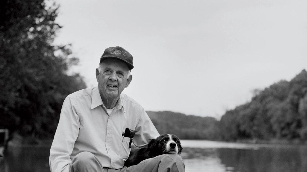 Wendell Berry pictured with a dog by the Kentucky River