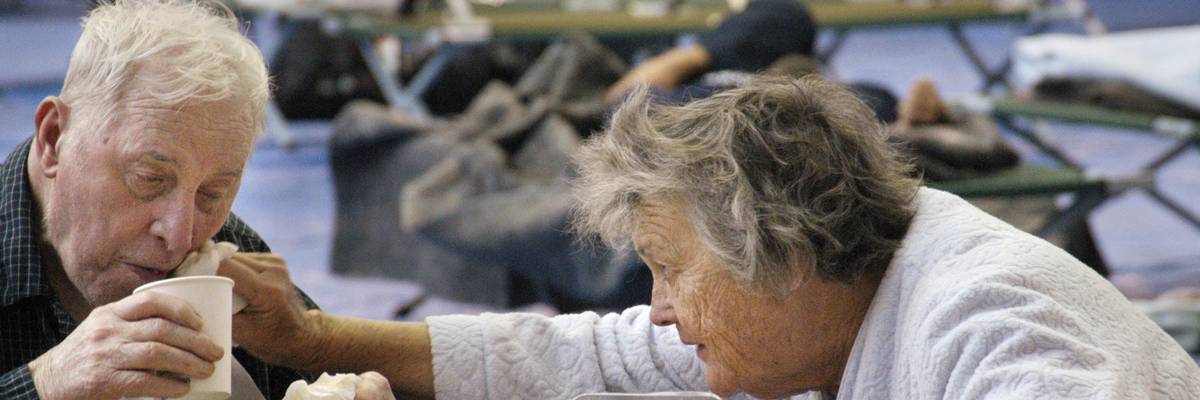 Wife helping her elderly husband at an emergency shetler