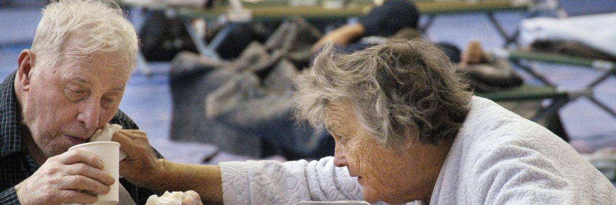 Wife helping her elderly husband at an emergency shetler