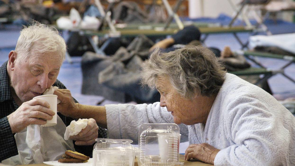 Wife helping her elderly husband at an emergency shetler
