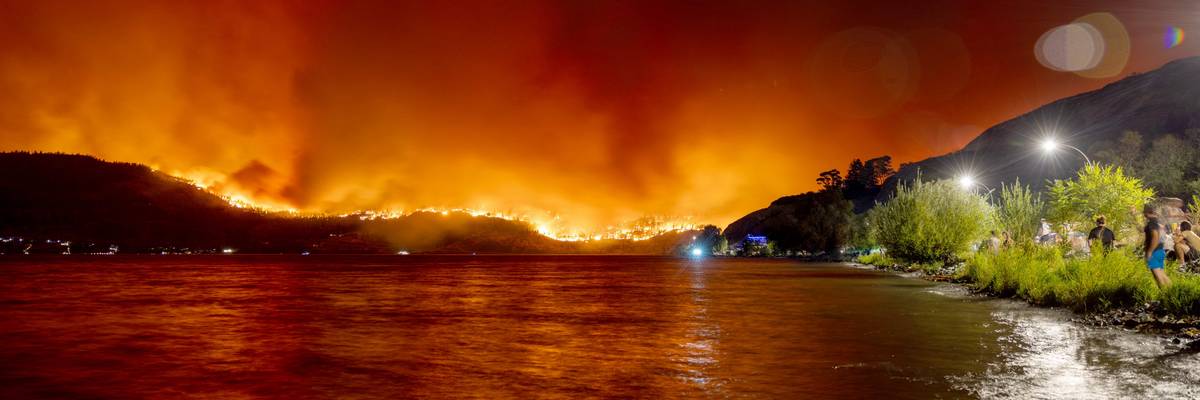 Wildfire in Canada burns over a hillside.