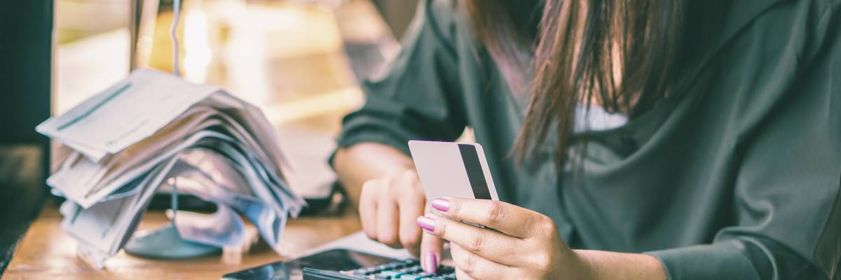 woman does bills while holding credit card
