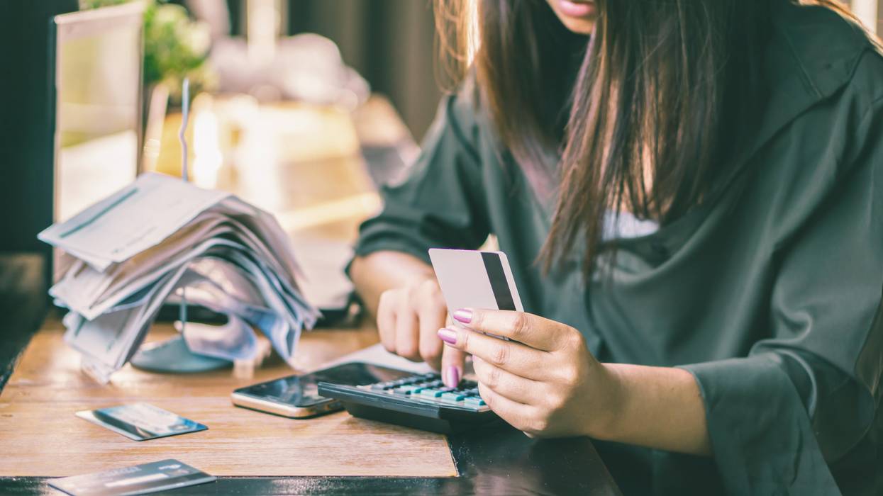 woman does bills while holding credit card