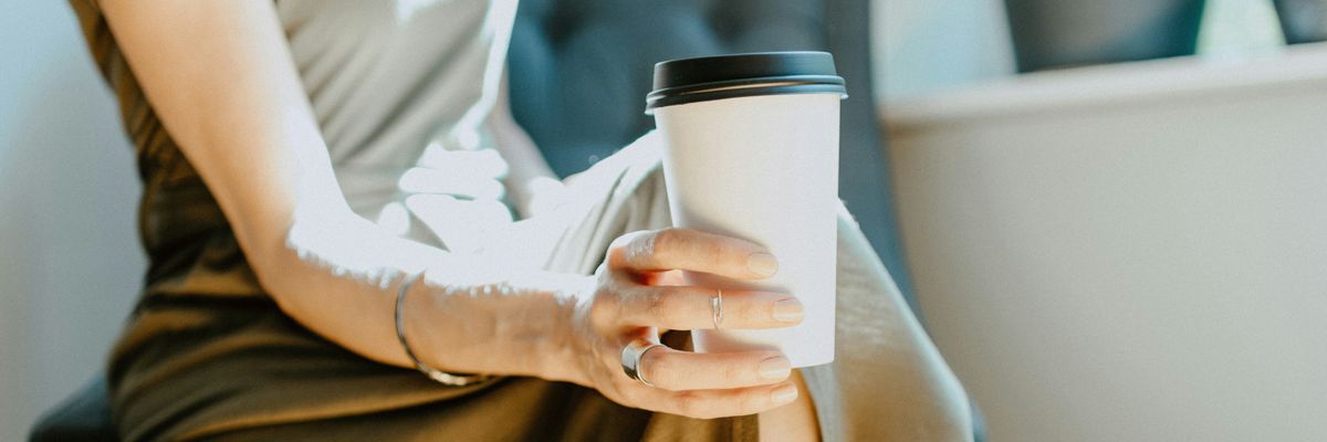 Woman holding single-use coffee cup.