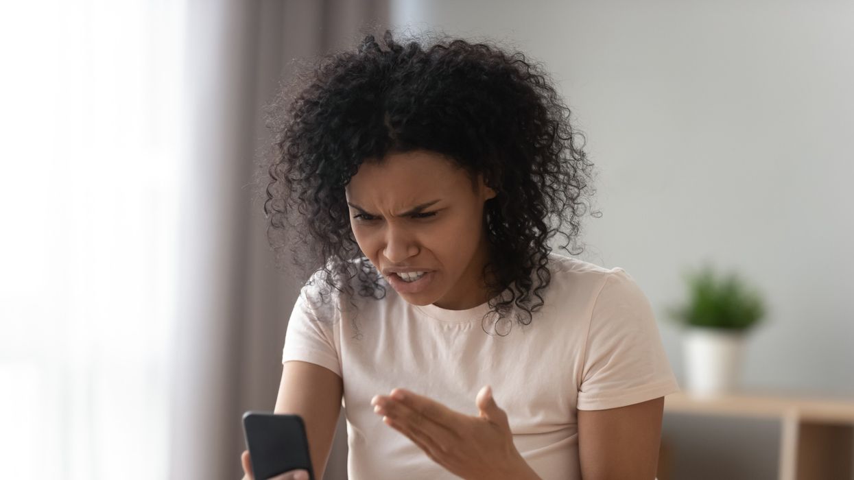 Woman holding smartphone looks frustrated