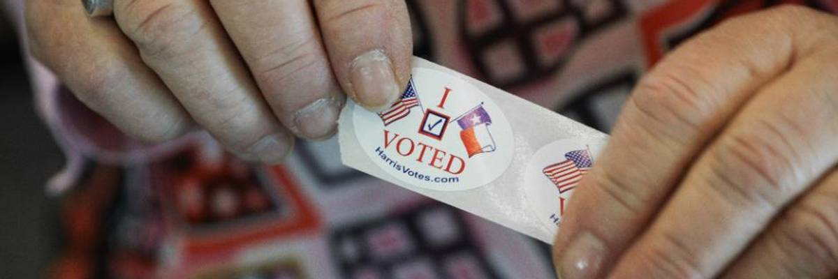 Woman holds an I Voted sticker.