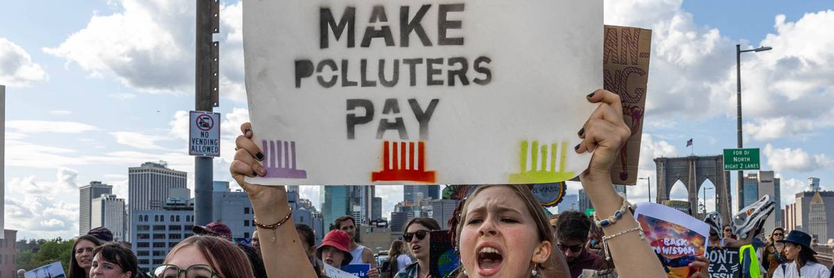 Woman holds sign reading, "Make polluters pay."