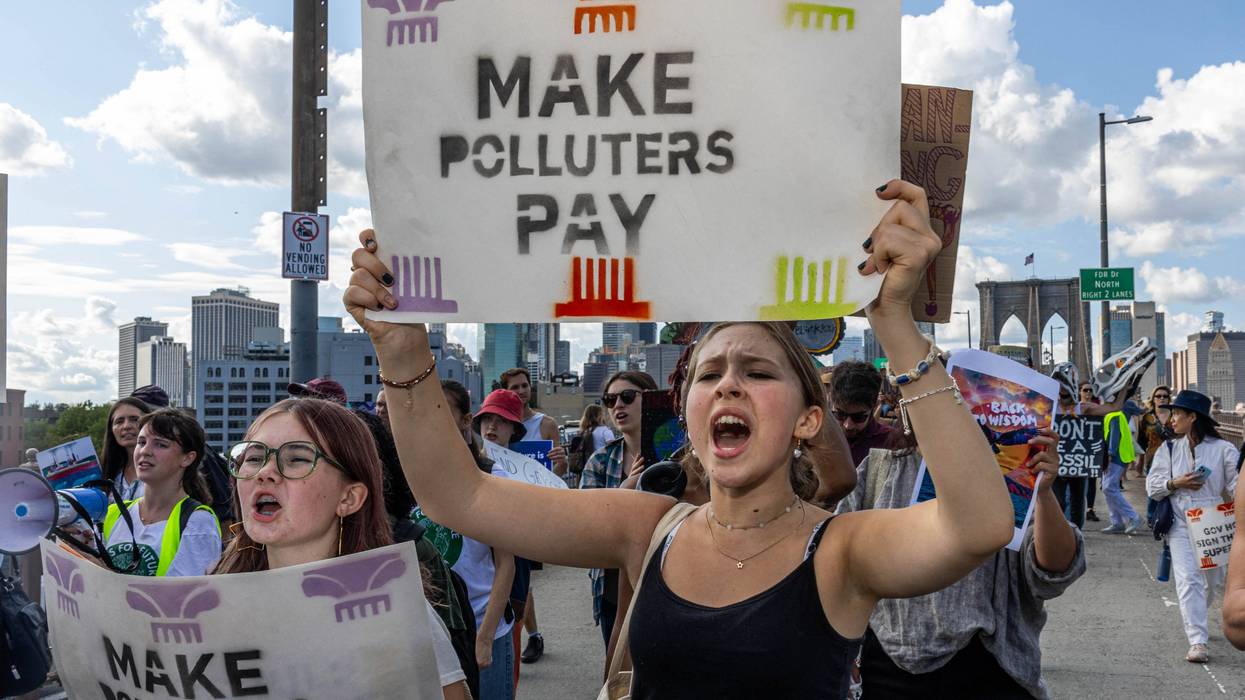 Woman holds sign reading, "Make polluters pay."