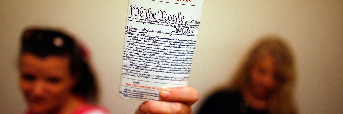 Woman holds up copy of U.S. Constitution.